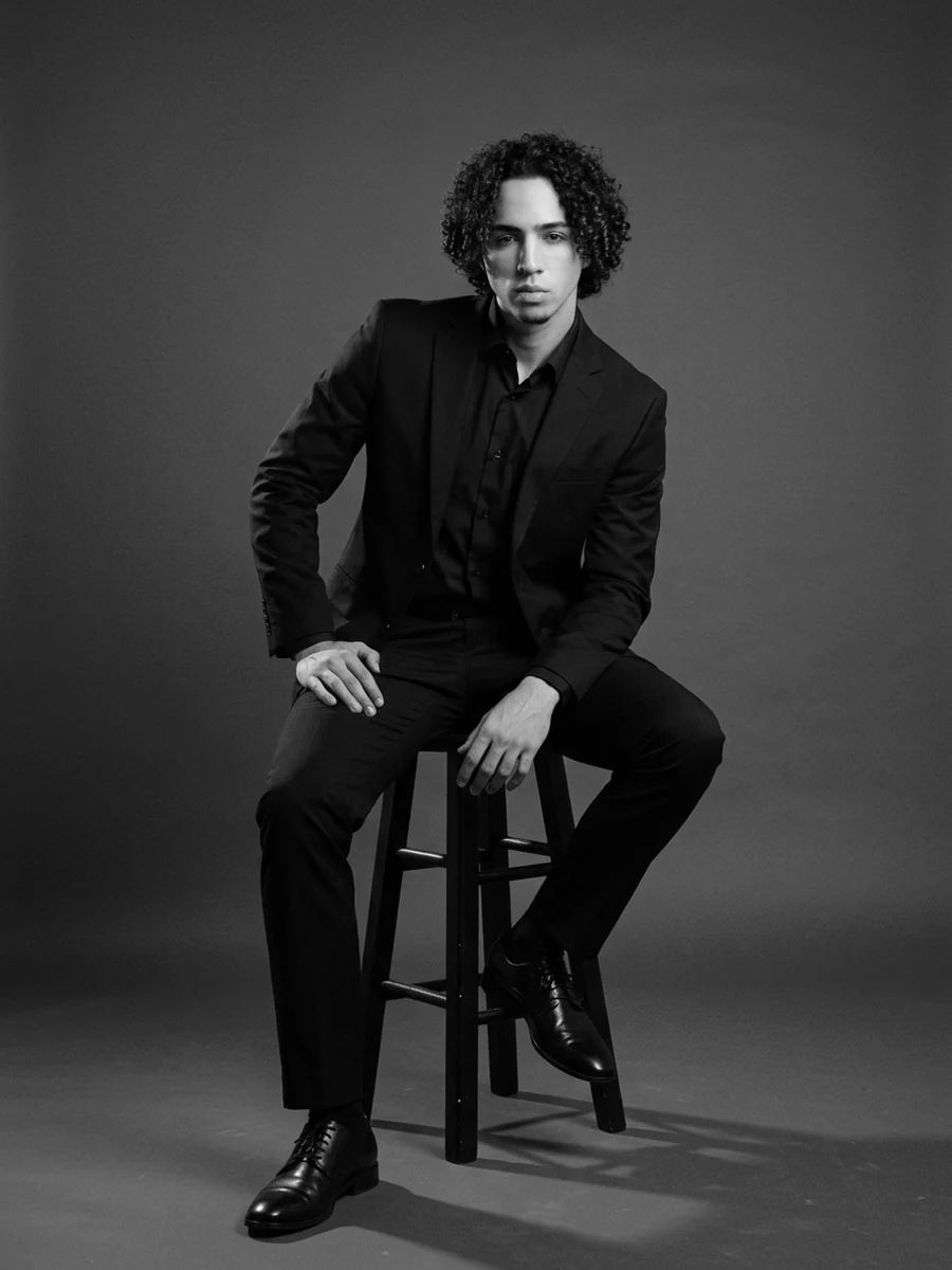 Youssef Belkhiria assis sur un tabouret, portrait noir et blanc